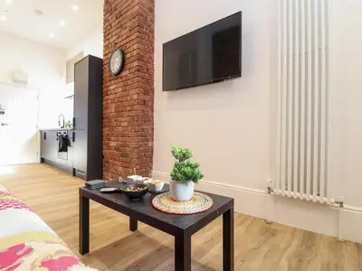 a living room with a table and a tv on a wall at The Dynar in Helston