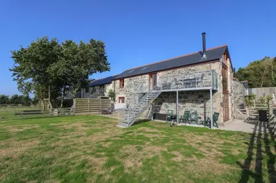 an old stone barn with a staircase in a yard at Pol Glas Hall in Helston