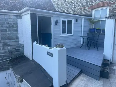 a wooden porch with a table on a house at Seasteps Padstow in Padstow