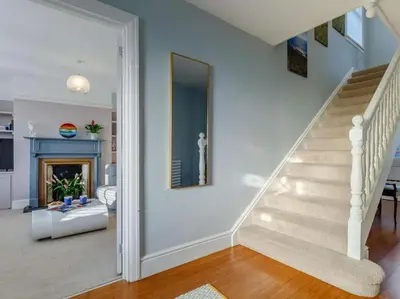 a living room with a staircase and a mirror at Mevagissey Holiday Home - sea view and parking in St Austell