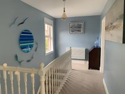 a blue room with a staircase and a mirror at Mevagissey Holiday Home - sea view and parking in St Austell