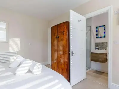 a white bedroom with a white bed and a wooden door at Mevagissey Holiday Home - sea view and parking in St Austell