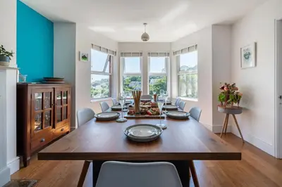 a dining room with a wooden table and chairs at Mevagissey Holiday Home - sea view and parking in St Austell