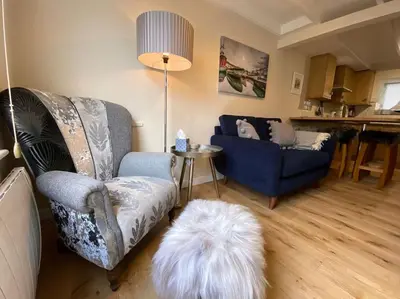 a living room with a couch and a white dog at Fulmar Cottage in Mevagissey