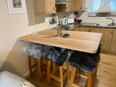 a wooden table with faux fur cushioned stools in a kitchen at Fulmar Cottage in Mevagissey
