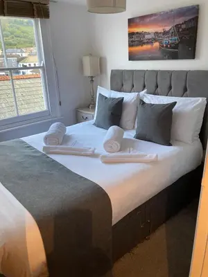 a large bed with two towels on top of it at Fulmar Cottage in Mevagissey
