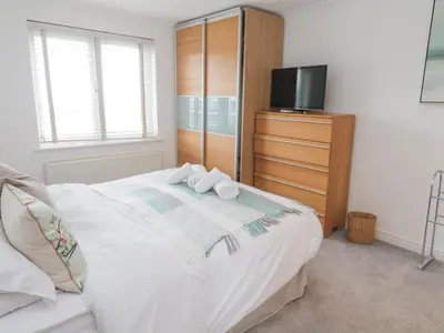 a bedroom with a bed with a dresser and a tv at 9 Headland Point in Newquay