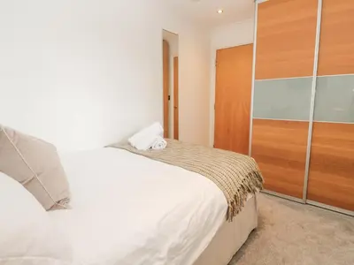 a bedroom with a white bed and a wooden closet at 9 Headland Point in Newquay
