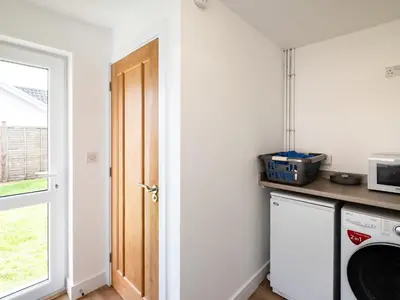 a laundry room with a washer and dryer next to a door at Obo's Retreat in Wadebridge