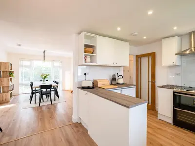 a kitchen with white cabinets and a table with chairs at Obo's Retreat in Wadebridge