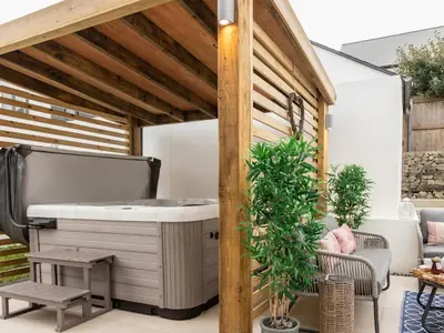 a deck with a hot tub on a patio at Driftwood in Newquay