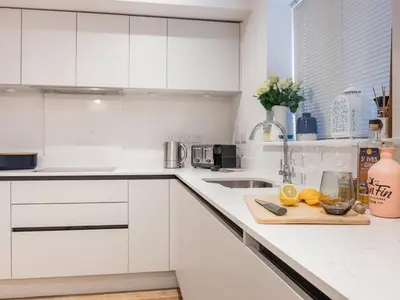 a kitchen with white cabinets and a cutting board with lemons at Driftwood in Newquay
