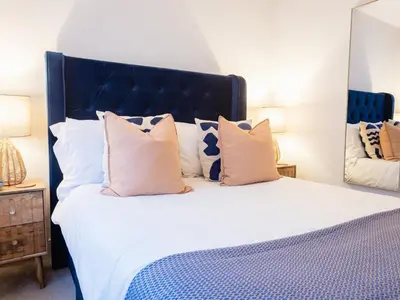 a bedroom with a large bed with a blue headboard and pillows at Driftwood in Newquay