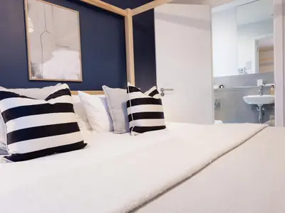 a white bed with black and white pillows on it at Driftwood in Newquay