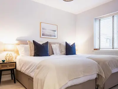 a white bedroom with a large bed with blue pillows at Driftwood in Newquay