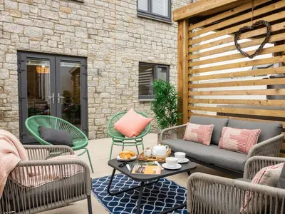 a patio with a couch and chairs and a table at Driftwood in Newquay