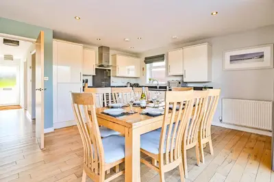 a kitchen and dining room with a wooden table and chairs at Lakeside House on Retallack Resort with Hot Tub 110 in Padstow