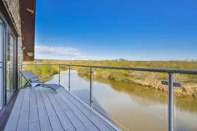 a chair sitting on a deck next to a river at Lakeside House on Retallack Resort with Hot Tub 110 in Padstow