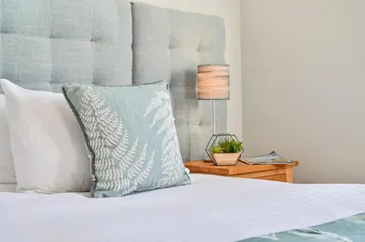 a bed with a blue pillow on top of it at Lakeside House on Retallack Resort with Hot Tub 110 in Padstow