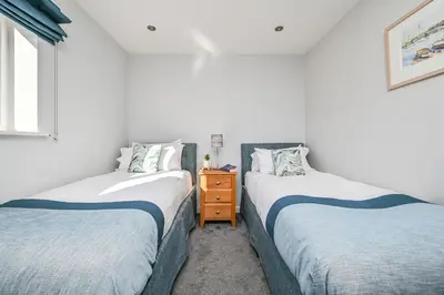 two twin beds in a room with white walls at Lakeside House on Retallack Resort with Hot Tub 110 in Padstow