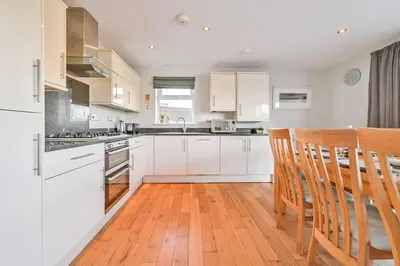 a kitchen with white cabinets and a table and chairs at Lakeside House on Retallack Resort with Hot Tub 110 in Padstow