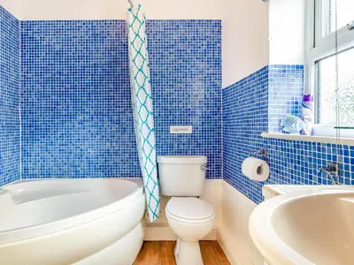 a blue tiled bathroom with a toilet and a tub at Mortreth in Porthtowan