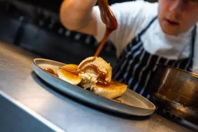 a person is preparing a sandwich on a plate at The Kingswood in St Austell