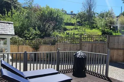 a fence with a chair and a blanket on it at Bijou Coastal Apartment in Polperro With Hot Tub, Onsite Parking 5 min Downhill Walk To Village in Polperro