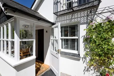 a white house with a door and a window at Bijou Coastal Apartment in Polperro With Hot Tub, Onsite Parking 5 min Downhill Walk To Village in Polperro