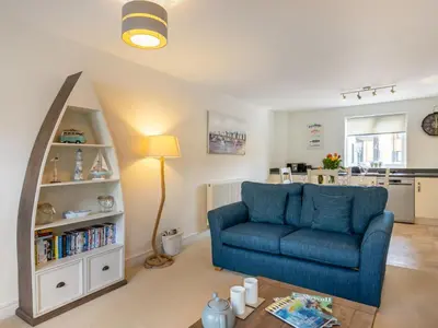 a living room with a blue couch and a book shelf at Apartment The Saltings by Interhome in St Austell