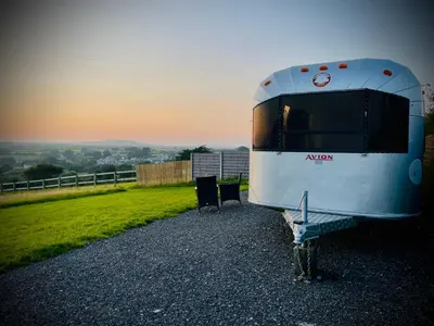 a trailer parked on the side of a field at WildView Cosy Glamping with Outdoor Bath and stunning scenery in Helston