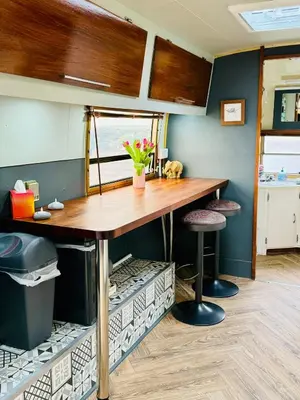a kitchen with a table and stools in a room at WildView Cosy Glamping with Outdoor Bath and stunning scenery in Helston