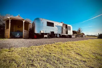 a trailer is parked next to a shed at WildView Cosy Glamping with Outdoor Bath and stunning scenery in Helston
