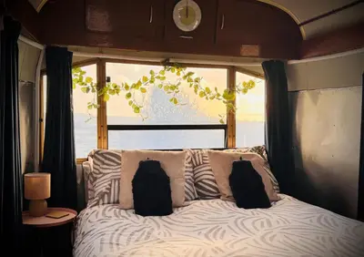 a bed with two pillows in front of a window at WildView Cosy Glamping with Outdoor Bath and stunning scenery in Helston