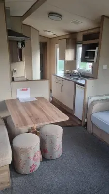 a small kitchen with a table and stools in a caravan at Newquay Caravan, Newquay Bay Resort Jetts View 104 in Newquay