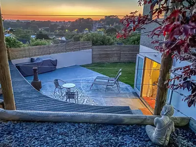 a backyard with a wooden deck with a table and chairs at High View in Truro