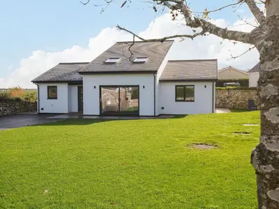 a white house with a green yard at Zephyr in Helston