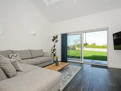 a living room with a couch and a large window at Zephyr in Helston