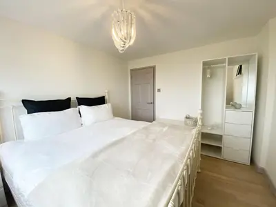a large white bed in a bedroom with a chandelier at 18 Coastline apartment in Newquay
