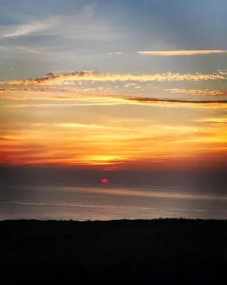 a sunset over the ocean with the sun in the distance at 18 Coastline apartment in Newquay