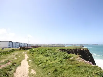 a dirt road next to the ocean at 18 Coastline apartment in Newquay