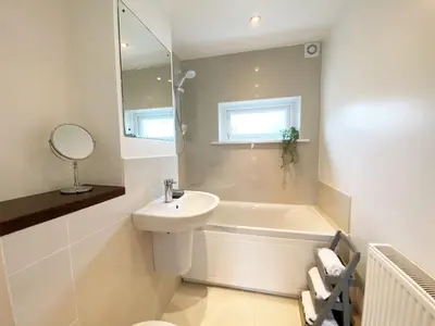 a white bathroom with a sink and a bath tub at 18 Coastline apartment in Newquay