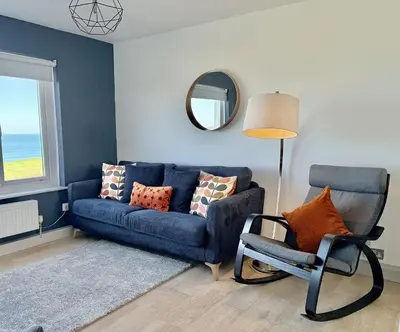 a living room with a blue couch and a chair at 18 Coastline apartment in Newquay