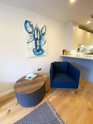 a living room with a table and a blue chair at 2 Watergate View in Newquay