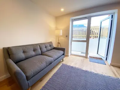 a living room with a couch and a large sliding glass door at 2 Watergate View in Newquay