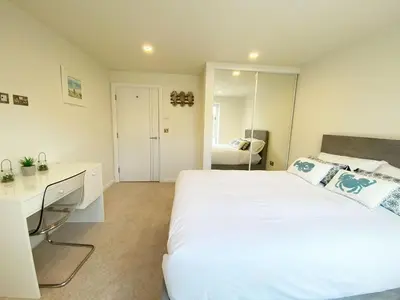 a bedroom with a large white bed and a desk at 2 Watergate View in Newquay