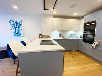 a kitchen with white cabinets and a counter top at 2 Watergate View in Newquay