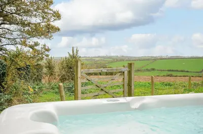 a bath tub in front of a fence with a gate at Pol Glas Cabin in Helston