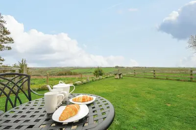 a table with plates of croissants and cups on it at Pol Glas Cabin in Helston