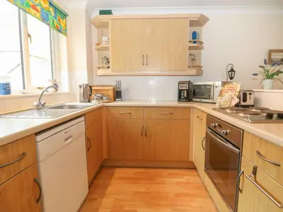 a kitchen with wooden cabinets and a sink at Morton Cottage in Falmouth